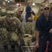 U.S. Sailors lift a simulated patient in a stretcher during a mass casualty drill in the hangar bay