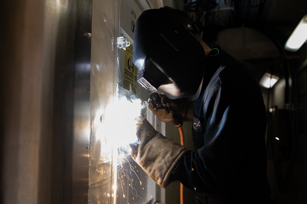 U.S. Sailor welds a dogging wrench bracket