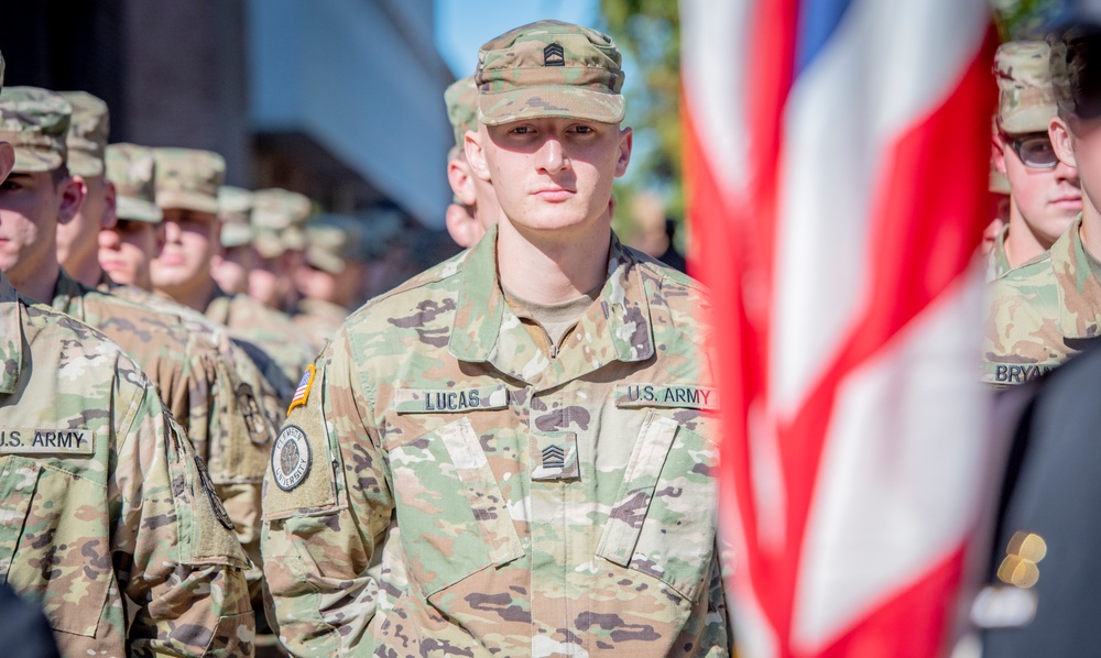 Army ROTC cadet in formation with flag