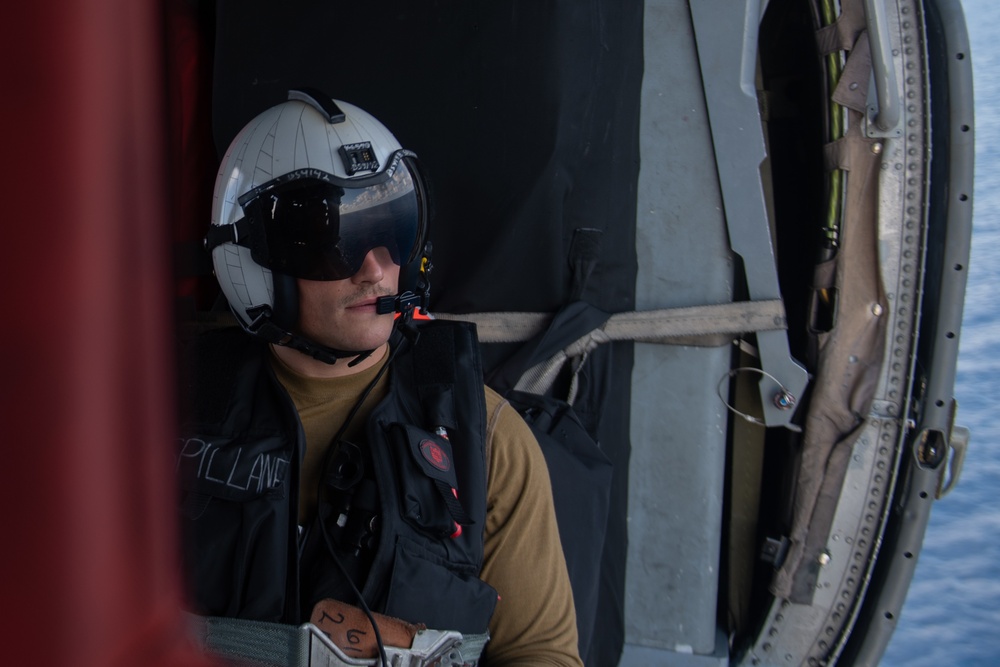 U.S Navy Naval Aircrewman observes flight operations from an MH-60S Sea Hawk