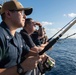 U.S. Sailors fish off the fantail