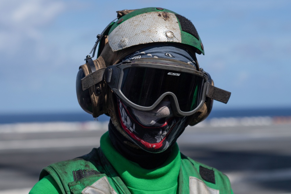 U.S. Navy Aviation Boatswain's Mate (Handling) Airman Apprentice Chris Blaisdell, from Lancaster, California, awaits An F/A-18F Super Hornet