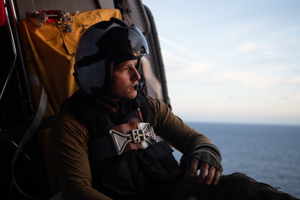 U.S Navy Naval Airc Crewman monitors flight activity from the cabin of an MH-60S Sea Hawk in the Atlantic Ocean