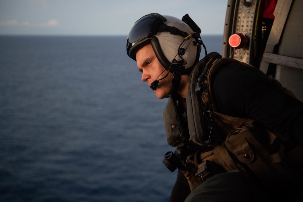 U.S Navy Naval Aircrewman monitors flight activity from the cabin of an MH-60S Sea Hawk in the Atlantic Ocean