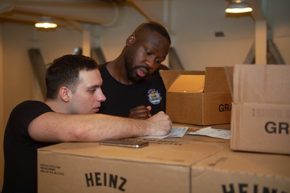 U.S. Navy Culinary Specialist 3rd Class Navard Robinson (right), from Fort Lauderdale, Florida, and Culinary Specialist Seaman Chris Bansemer, from Austin, Texas, inventory supplies in a dry provision storeroom