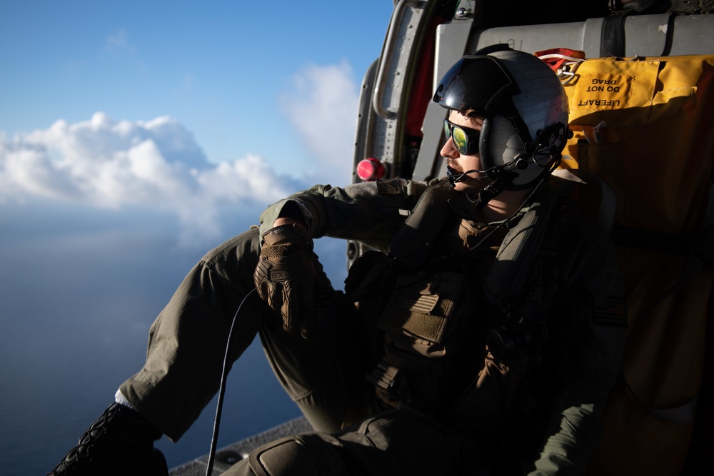 U.S. Navy Naval Air Crewman Atlantic Ocean monitors flight activity from the cabin of an MH-60S Sea Hawk