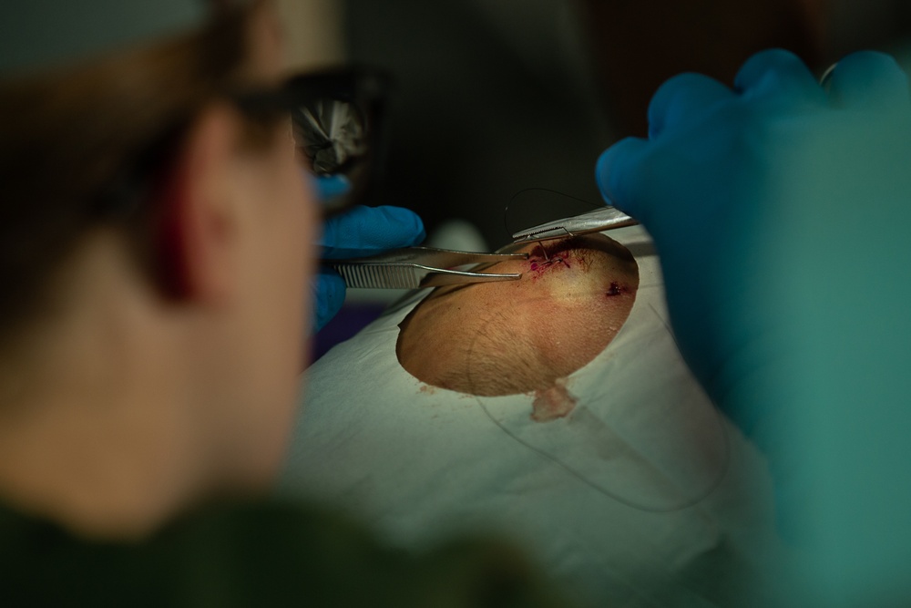 Corpsman performs suture on Marine