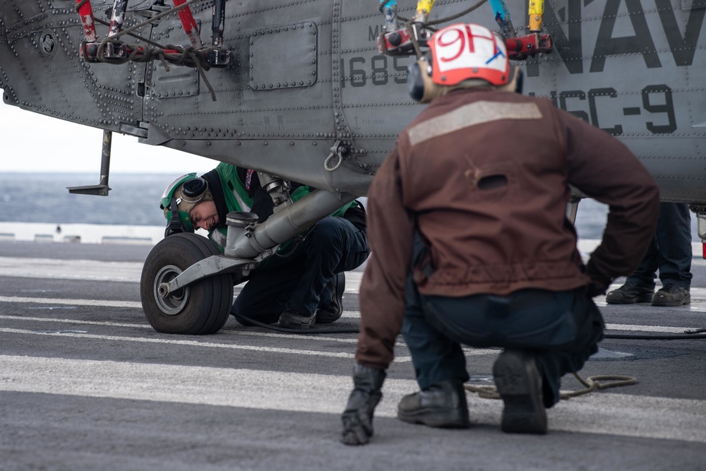 U.S. Sailor services the tail tire on an MH-60S Sea Hawk assigned to Helicopter Sea Combat Squadron (HSC) 9