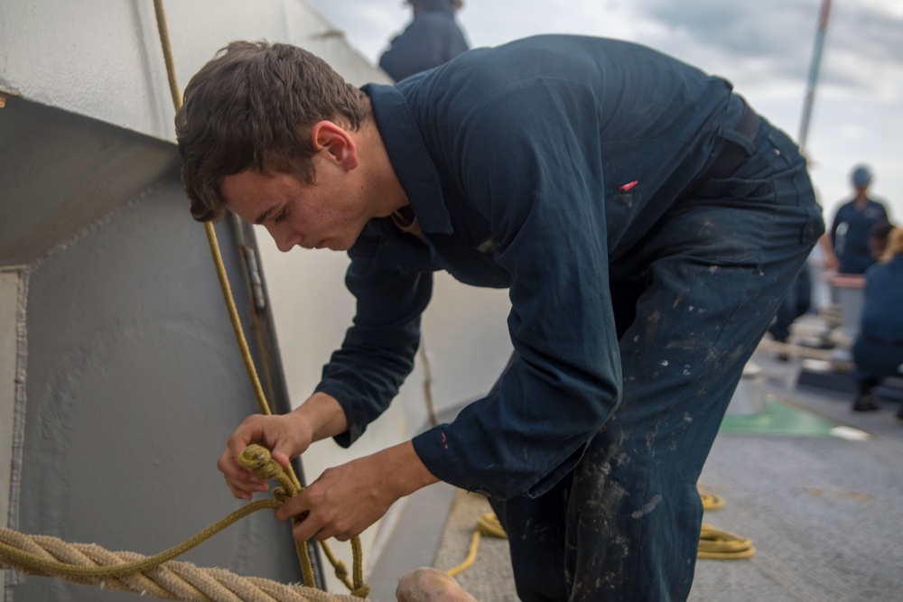 Sailor ties messenger line around a mooring line