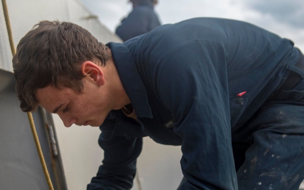Sailor ties messenger line around a mooring line