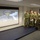 A group of U.S. Navy personnel in various uniforms are gathered in a briefing room, viewing a projected presentation about Admiral Chester W. Nimitz and the Battle of Midway. The slide displays a portrait of Admiral Nimitz along with a quote attributed to him as Commander in Chief of the U.S. Pacific Fleet. An American flag is visible on the wall in the background.