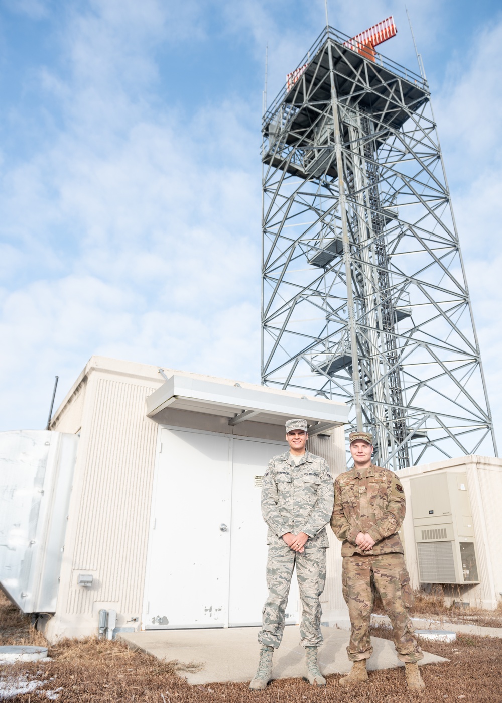 Electrical power production Airmen pose for a photo in front of a radar tower generator