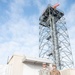 Electrical power production Airmen pose for a photo in front of a radar tower generator