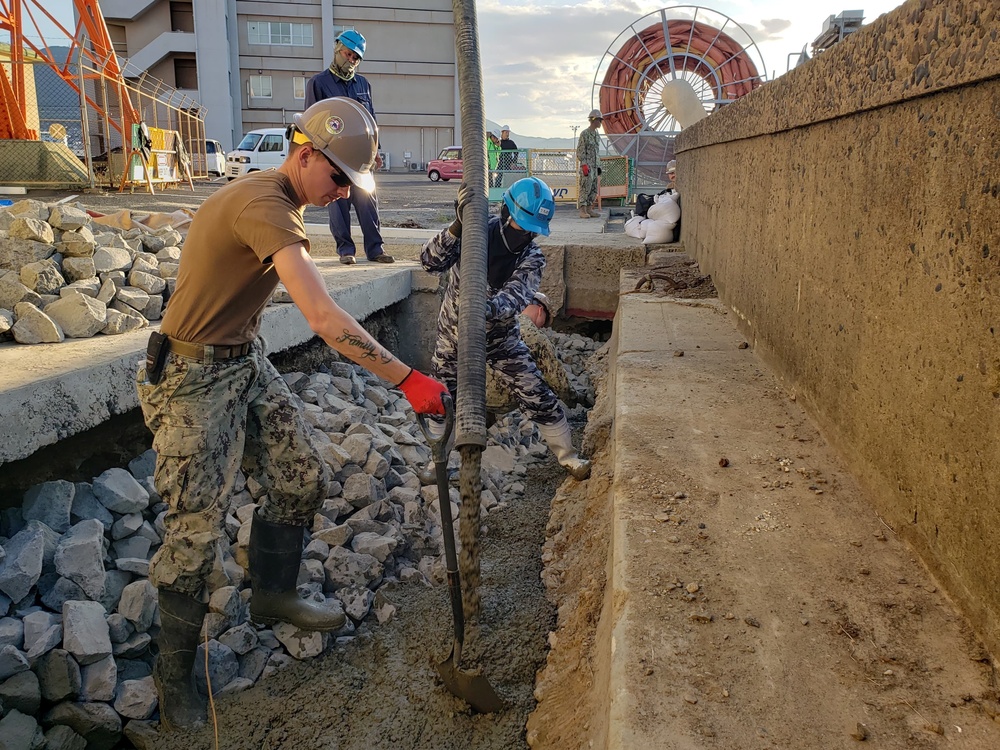 U.S. Navy Seabees deployed with Naval Mobile Construction Battalion 5’s Detail Sasebo place concrete for the seawall port repairs on Commander Fleet Activities Sasebo