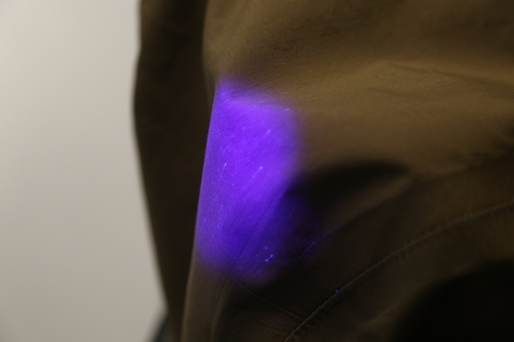 A black light reveals simulant particles on a protective suit.