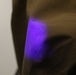 A black light reveals simulant particles on a protective suit.