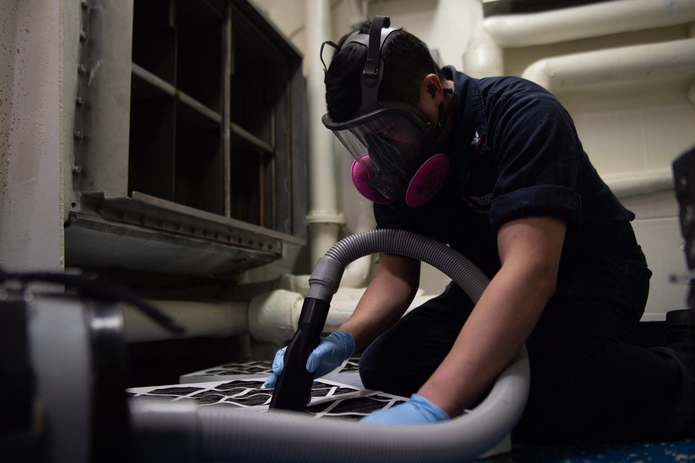 U.S. Navy Aviation Electronics Technician 3rd Class Cyrille Somera, from Menifee, California, vacuums an air filter