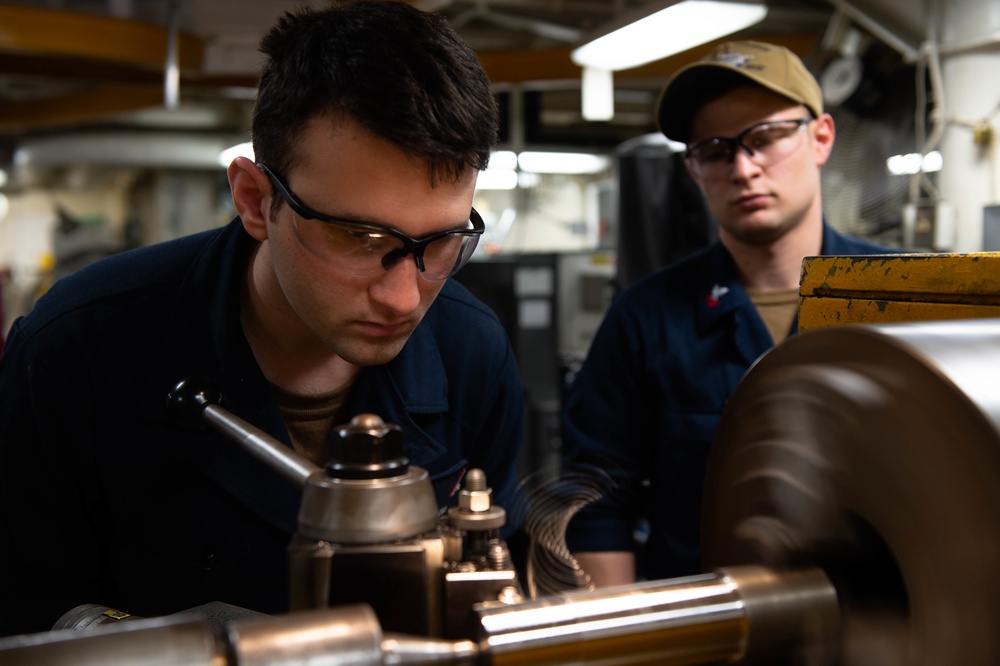 U.S. Sailors operate lathe