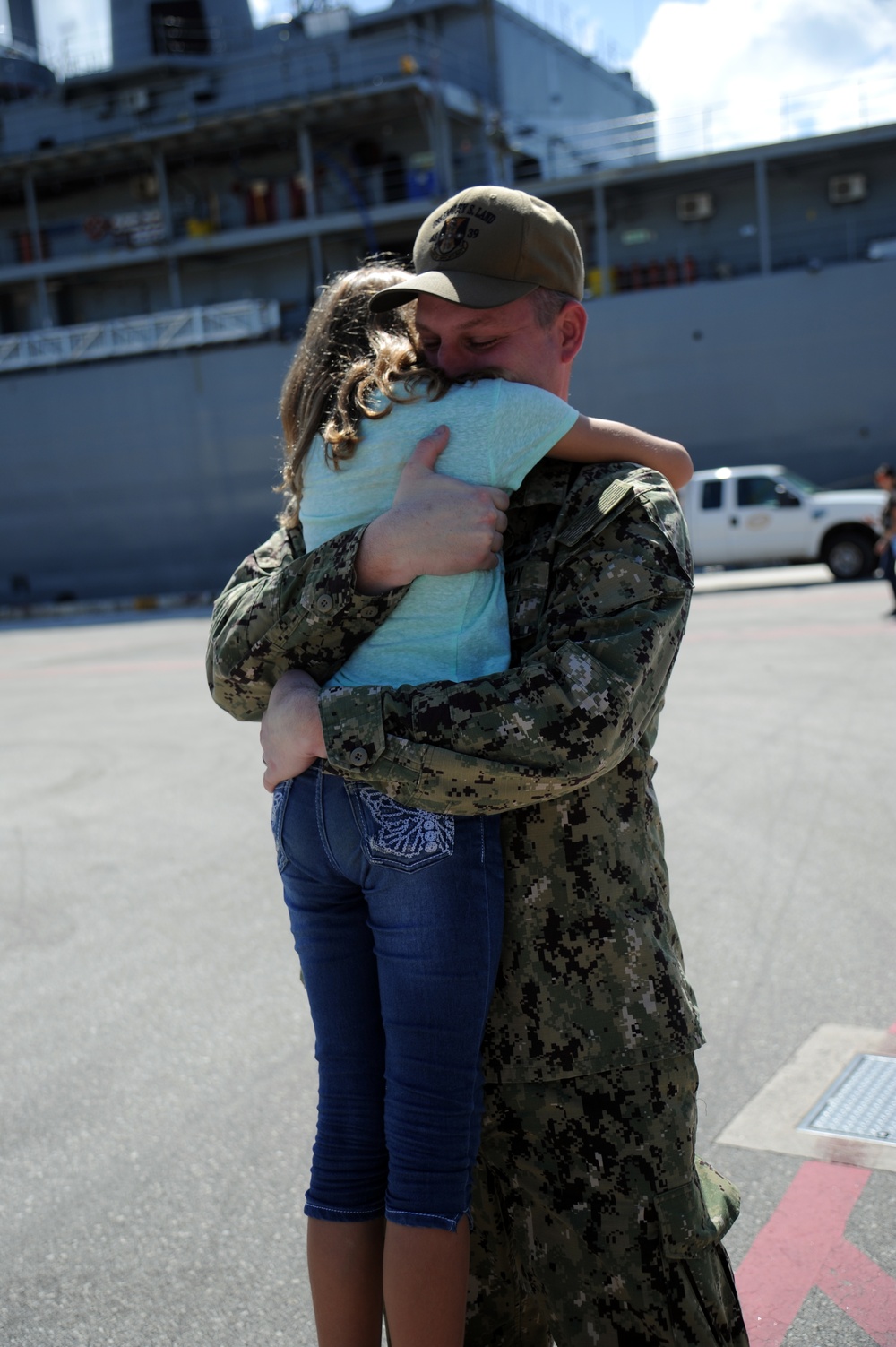 Chief Hull Maintenance Technician Leonard Roach, assigned to the submarine tender USS Emory S. Land (AS 39), hugs his daughter during a homecoming gathering