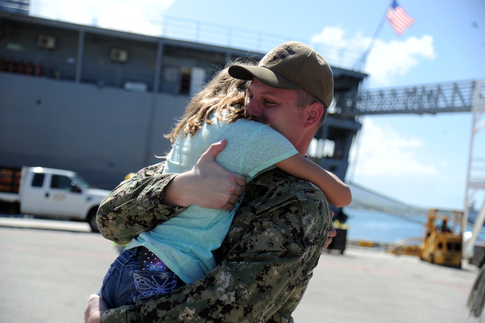 Chief Hull Maintenance Technician Leonard Roach, assigned to the submarine tender USS Emory S. Land (AS 39), hugs his daughter during a homecoming gathering at Polaris Point
