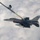 An F-16 Fighting Falcon jet fighter is conducting an aerial refueling operation with a tanker aircraft. The fighter jet, marked with tail code 'ET' and '96 TW' (96th Test Wing), serial number AF70353, is connected to a refueling boom extending from the tanker above. The aircraft is flying above a cloud layer and carries what appears to be an air-to-air missile on its centerline station.