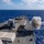 USS Wayne E. Meyer (DDG 108) Live Fire exercise A naval warship, consistent with a U.S. Navy Arleigh Burke-class guided-missile destroyer, is firing its forward deck gun during what appears to be a live-fire exercise at sea. A large plume of white-gray smoke is visible at the bow area, indicating a recent or ongoing gun discharge. The vessel is underway in open blue ocean under partly cloudy skies.