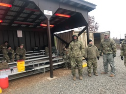 TF MED Soldiers gather under a hut