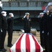 U.S. Sailors salute a service member’s remains on the pier