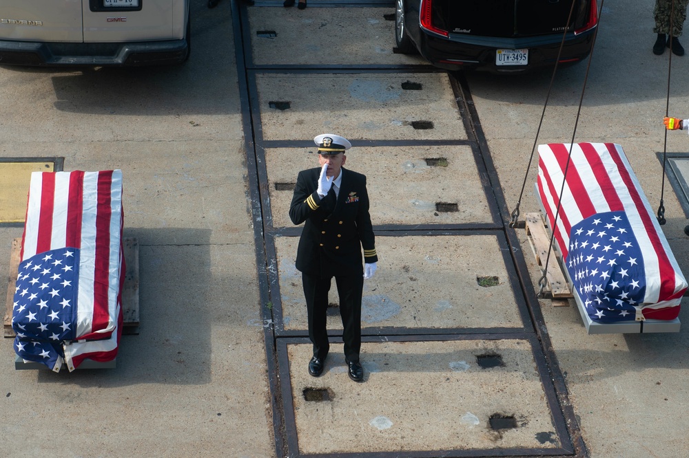 U.S. Sailor shouts to raise a casket from the pier to the aircraft carrier USS John C. Stennis (CVN 74)