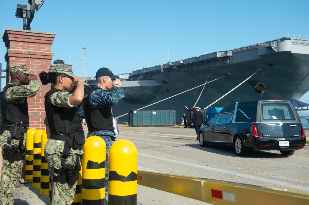 U.S. Sailors salute a hearse carrying a service member’s remains on the pier in preparation for a burial-at-se