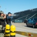 U.S. Sailors salute a hearse carrying a service member’s remains on the pier in preparation for a burial-at-se