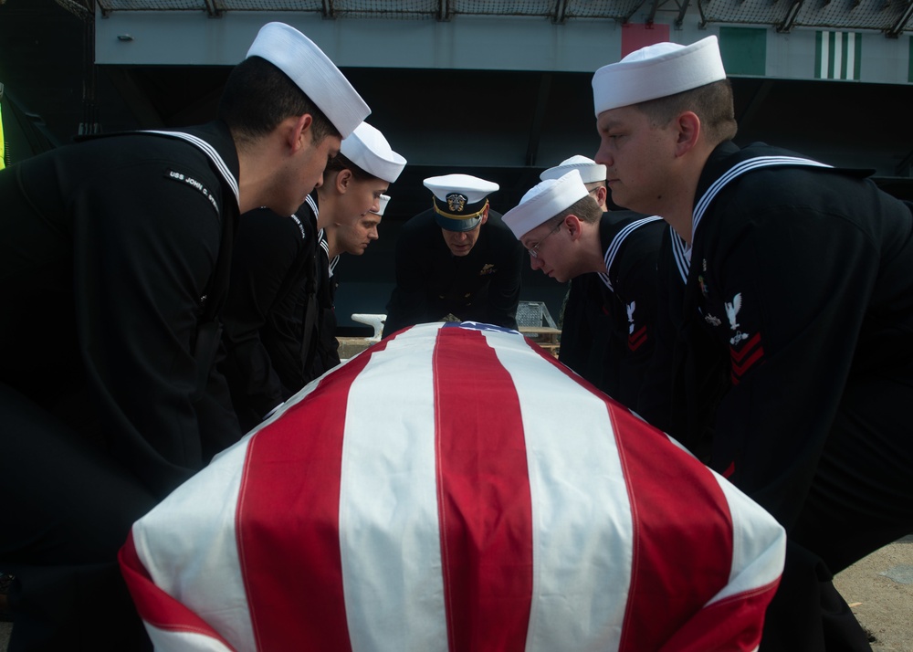 U.S. Sailors lower a service member’s remains