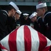 U.S. Sailors lower a service member’s remains