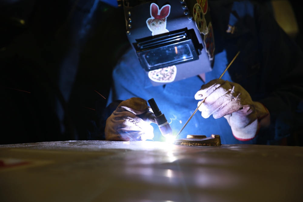 Hull Technician Clarissa Romero welds in the weld shop aboard the aircraft carrier USS Abraham Lincoln (CVN 72).
