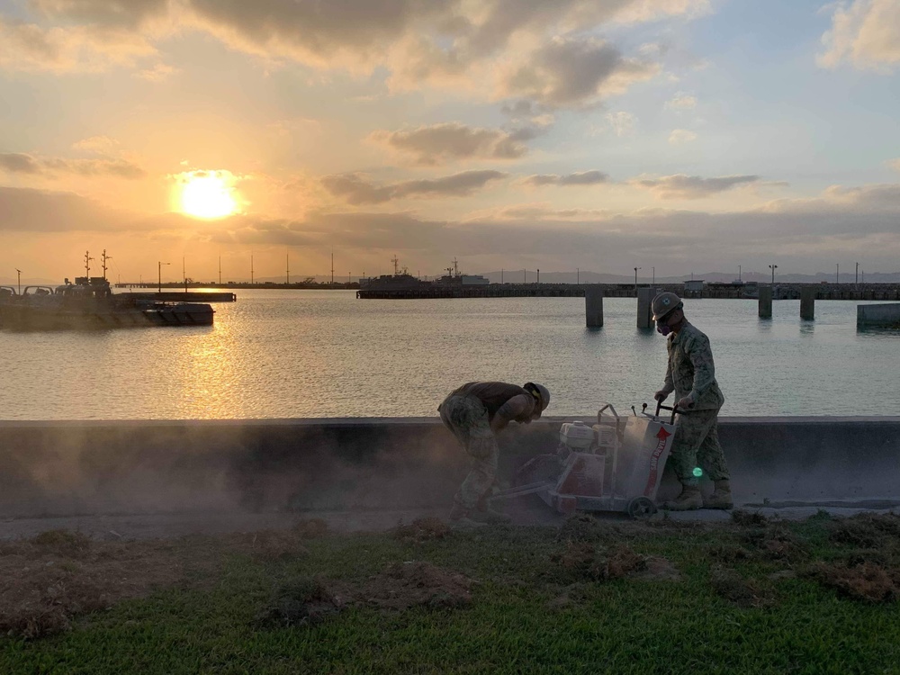 U.S. Navy Seabees replace sidewalks and repair a seawall on board Naval Base White Beach