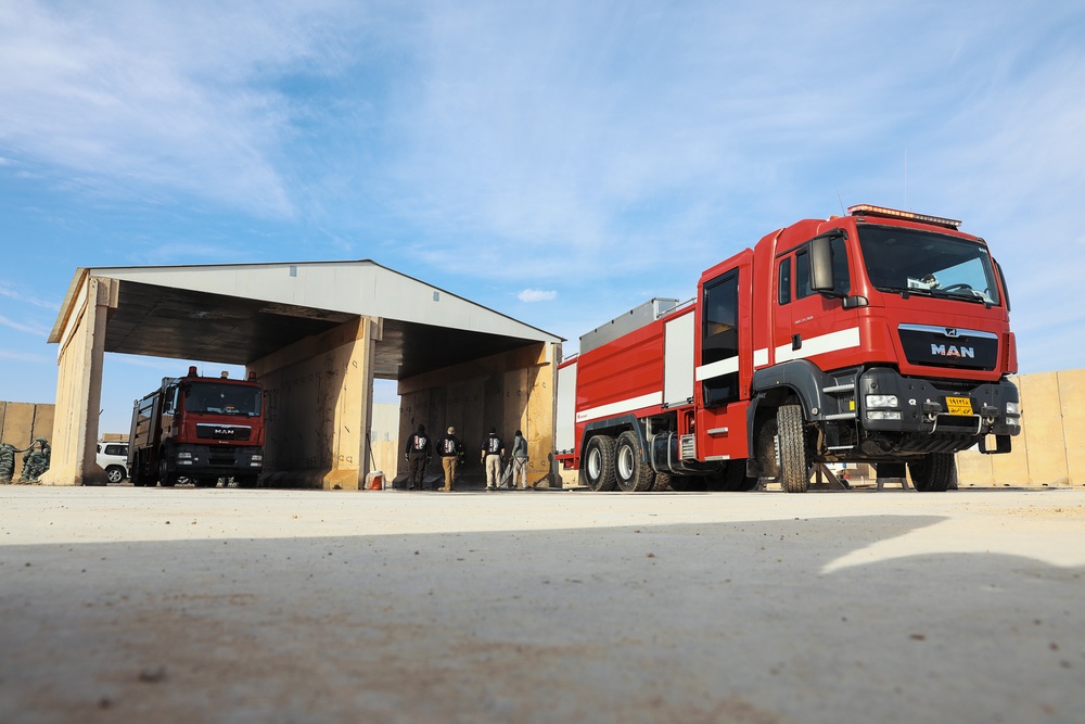 Civilian contractors clean fire truck bays