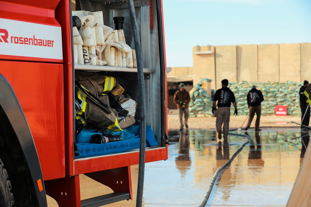 Civilian contractors clean fire truck bays