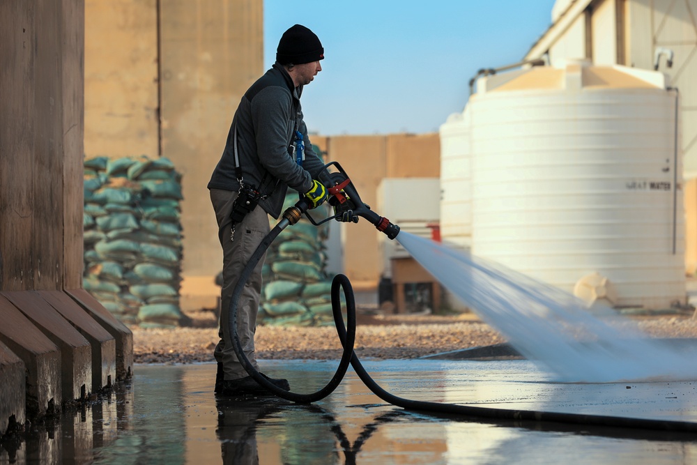 Civilian contractors clean fire truck bays