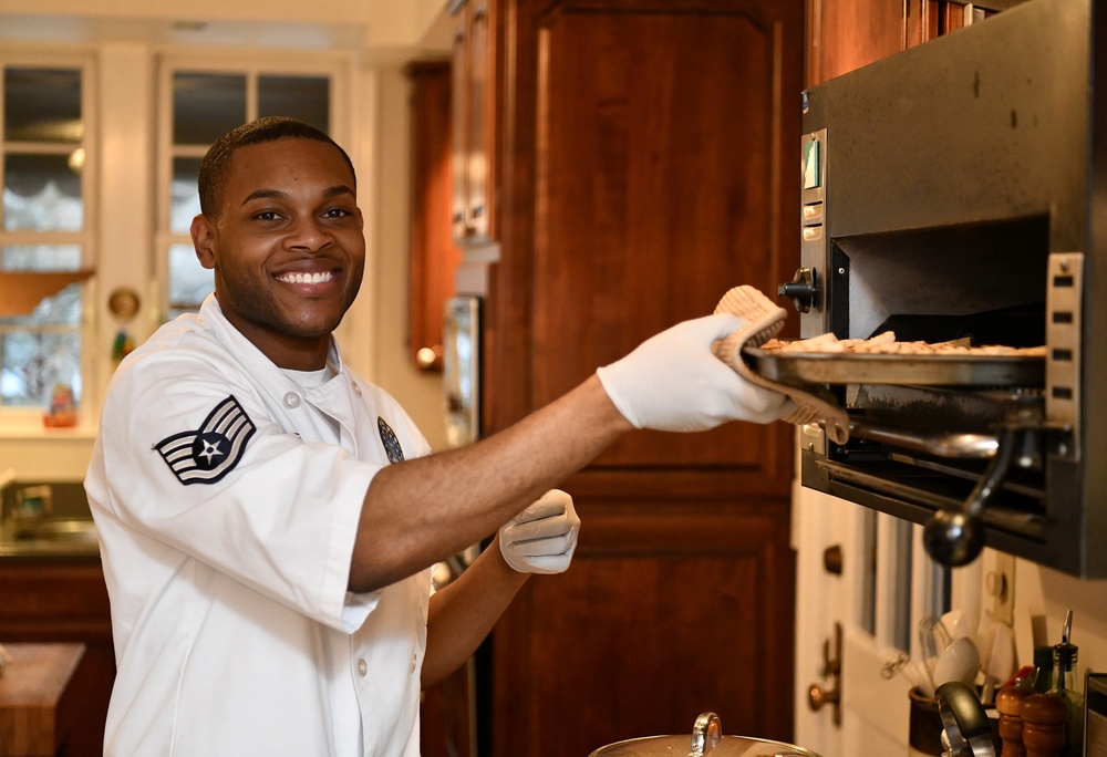 SSgt Martavious Miller assists as aide of the deputy commander during a Christmas party hosted by the commander and his family at the commander's official residence