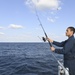 USS Normandy Sailor Fishes During Holiday Routine