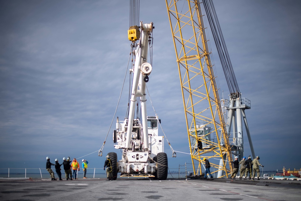 U.S. Sailors and contractors hoist an aircraft crane