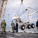 U.S. Sailors and contractors hoist an aircraft crane