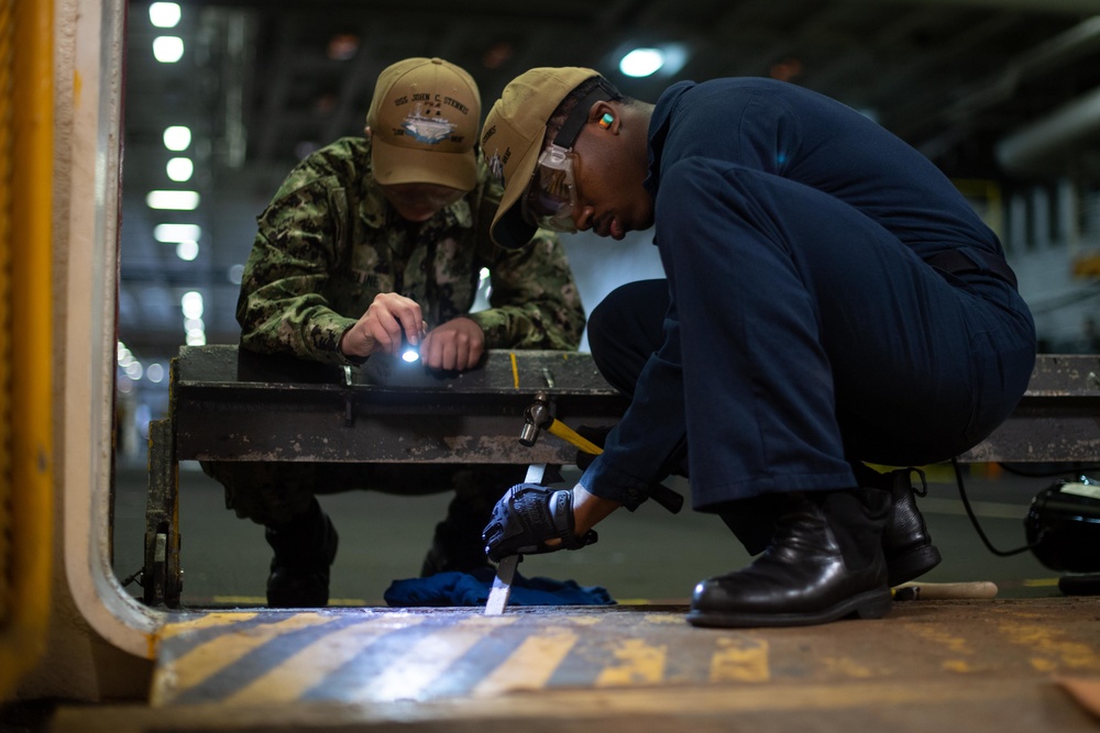 U.S. Sailors conduct maintenance on a weapons elevator