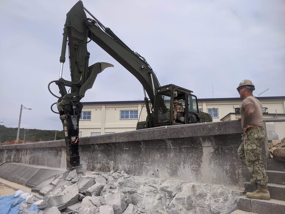 U.S. Navy Seabees with NMCB-5 repair a seawall on board White Beach Naval Facility