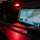 CBP Support to Super Bowl LIV A ruggedized tablet or handheld device displays a nautical/maritime navigation map application in a low-light environment illuminated by red lighting. The screen shows a coastal or waterway map with route lines, waypoints, and data overlays typical of military or professional maritime navigation software. The setting appears to be inside a vessel or vehicle cockpit during nighttime operations.