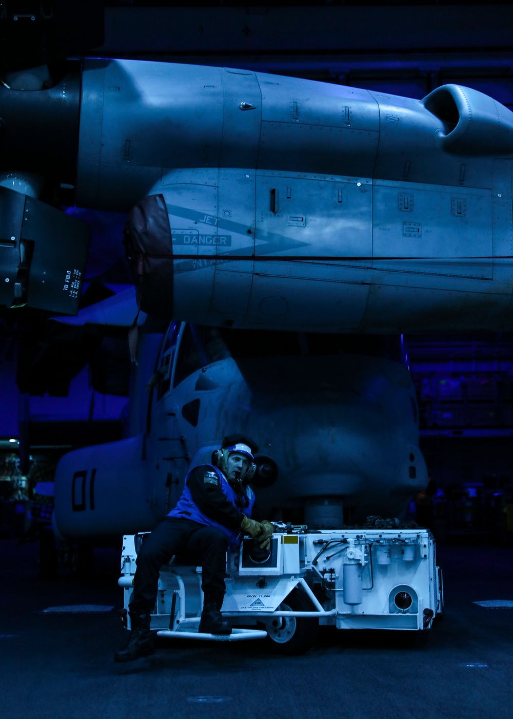 USS Makin Island Sailor reverses a MV-22B Osprey through the hangar bay.