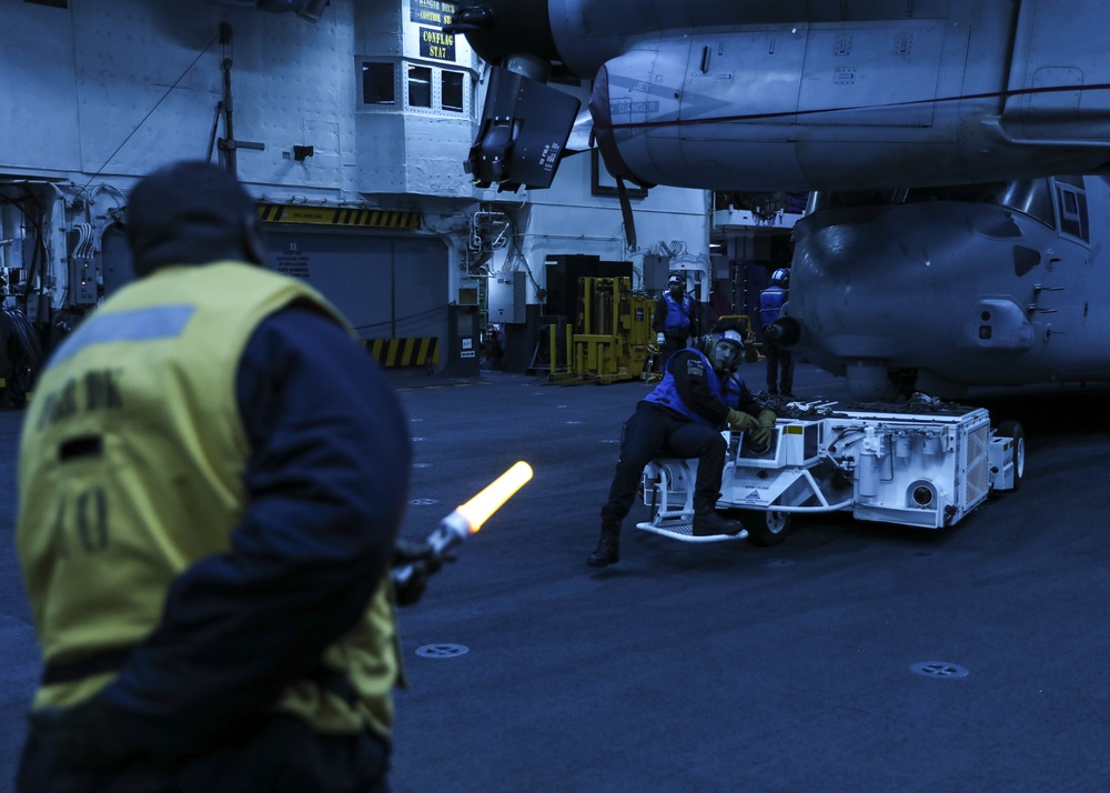 USS Makin Island Sailor reverses a MV-22B Osprey through the hangar bay.