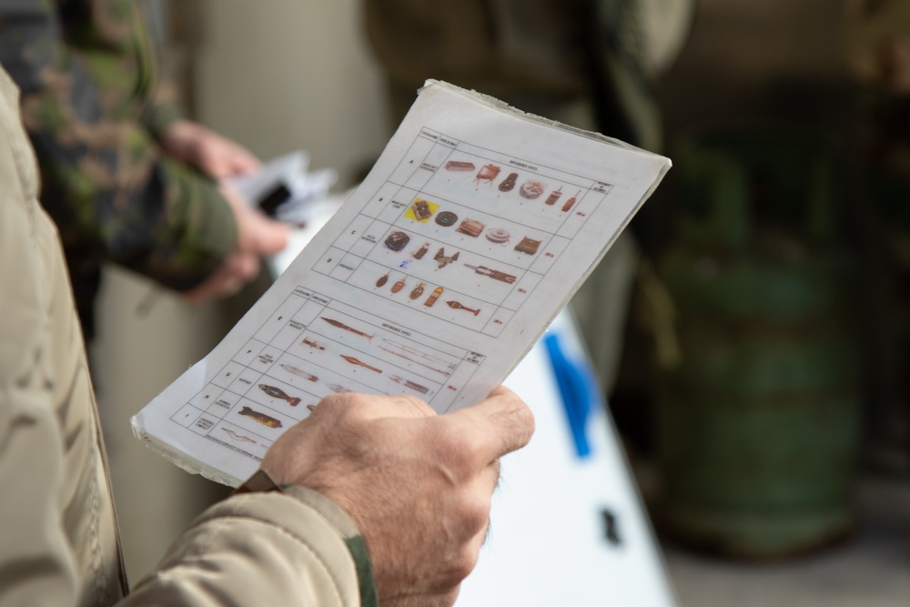 A Peshmerga soldier studies various types of unexploded ordnance