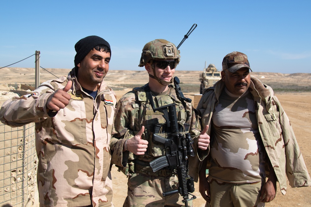 Iraqi and U.S. soldiers pose for a photograph along the perimeter of Al Asad Airbase