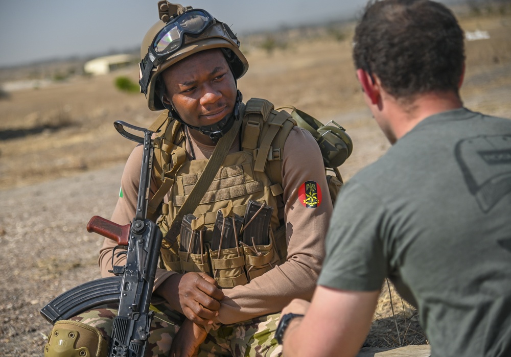 Soldier in the Nigerian Army simulates speaking to a village elder, played by a Soldier from the United Kingdom, during a drill as part of FLINTLOCK 20